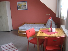 Zimmer mit Schreibtisch und Bett
